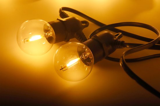 Twee warme, gloeiende transparante LED-lampjes van een lichtsnoer op een lichte achtergrond.