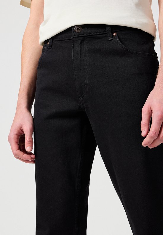 Detail van de voorkant van een zwarte jeans.