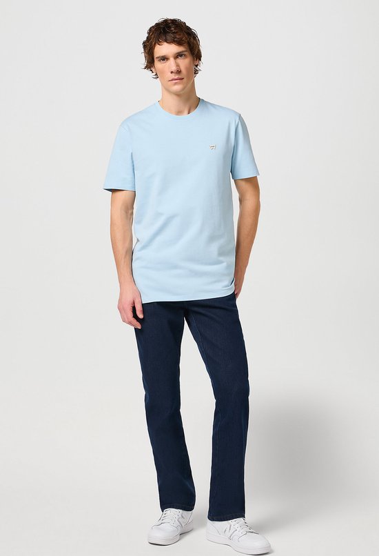 Man draagt een lichtblauwe T-shirt met korte mouwen en donkerblauwe jeans.