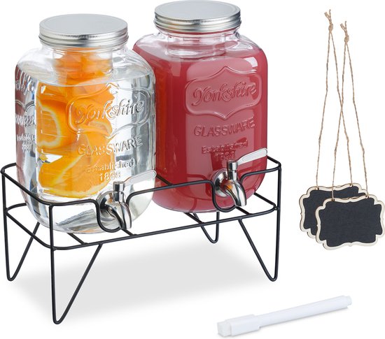 Dubbele glazen drankdispenser met sinaasappelschijfjes en rood sap, met losse krijtbordjes.