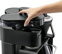 Hand vult het waterreservoir van het zwarte Melitta Epos koffiezetapparaat.