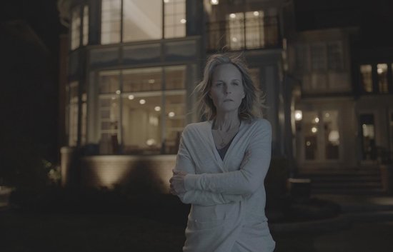 Helen Hunt staat 's nachts buiten met armen over elkaar, een landhuis op de achtergrond.
