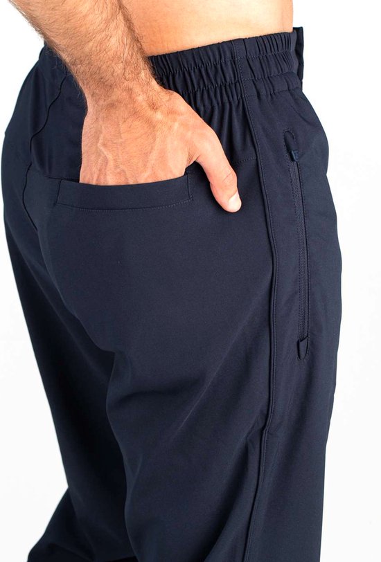 Close-up van de achterkant van een zwarte joggingbroek, man steekt hand in een steekzak.