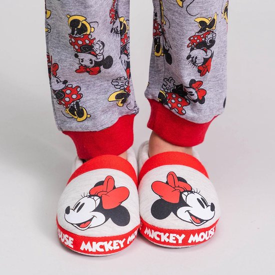 Voeten in witte pantoffels met Mickey Mouse opdruk, met een grijze broek met Mickey Mouse print.