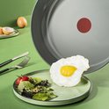 Poêle grise avec Thermo-Spot rouge. Un œuf au plat avec salade et tomate sur une assiette vert clair.