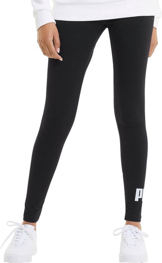 Gedeeltelijk beeld van een vrouw in zwarte legging met Puma-logo op de zijkant, gedragen met witte sneakers.