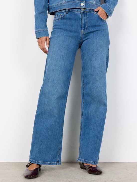 Close-up van de pasvorm van een lichtblauwe jeans met wijde pijpen, gecombineerd met een denim jasje.