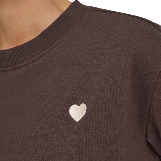 Detail van de bruine sweater met witte hart-applicatie op de linkerborst.