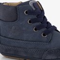 Detail van donkerblauwe babyschoen met veters, suède en gestreept logo.