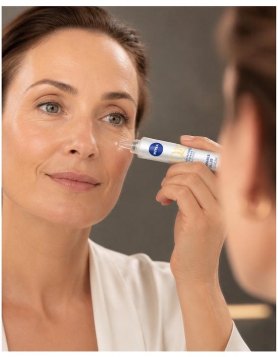 Een vrouw met bruin haar brengt Nivea Q10 Anti-Rimpel Expert Serum aan op haar oogcontour.
