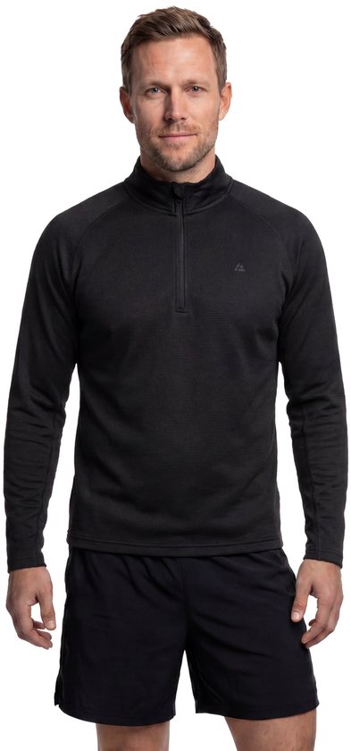 Man in een zwart sportshirt met halve rits en zwarte sportbroek.