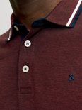 Close-up van de kraag en knopen van een donkerrode polo met logo.