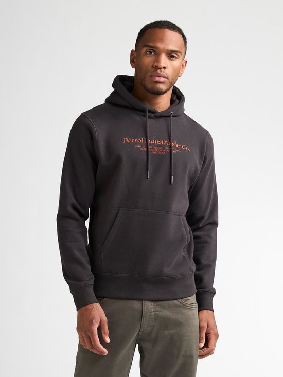 Donkere hoodie met oranje opdruk 'Petrol Industries & Co.', op een man.