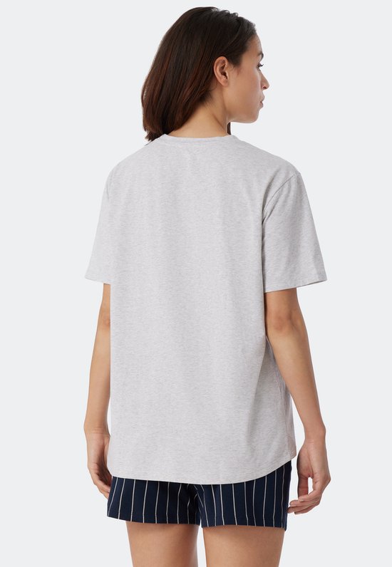 Une femme porte un t-shirt gris chiné à manches courtes et un pantalon à rayures bleu foncé.