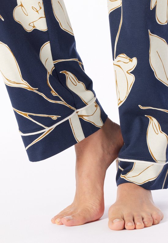 Detail van de enkels van de pyjamabroek met donkerblauwe basis, wit bloemmotief en witte bies.