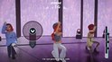 Drie K-Pop-dansers met rode en paarse achtergrond. Twee vrouwen en een man dansen op een podium, één met een blauwe trui en ster.