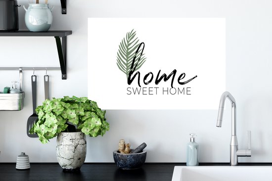 Witte muursticker met zwarte 'home' tekst, 'SWEET HOME' in drukletters en een groen palmblad.