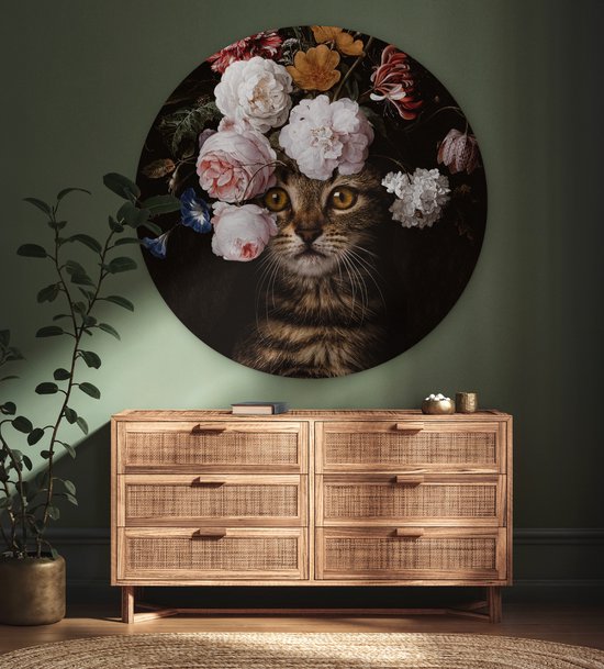 Ronde muurcirkel met kat met bloemenkrans, boven een dressoir.