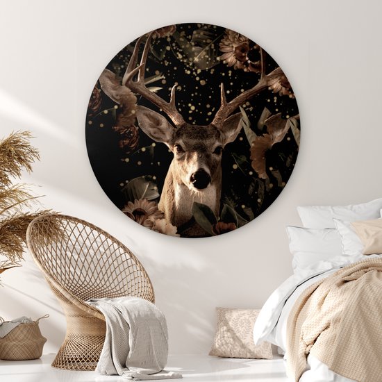Ronde muurcirkel met een hertenkop en bloemen, in een slaapkamer bij een bed.