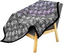 Grijze fauteuil met een deken met bloemenpatroon erop. De deken is zwart met witte bloemen en heeft een zwarte pluizige rand.
