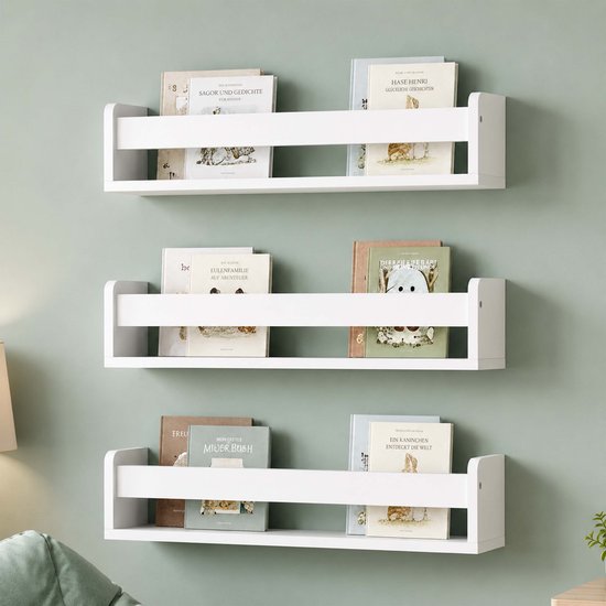 Drie witte kinderboekenplanken met diverse kinderboeken erop aan een lichtgroene muur.