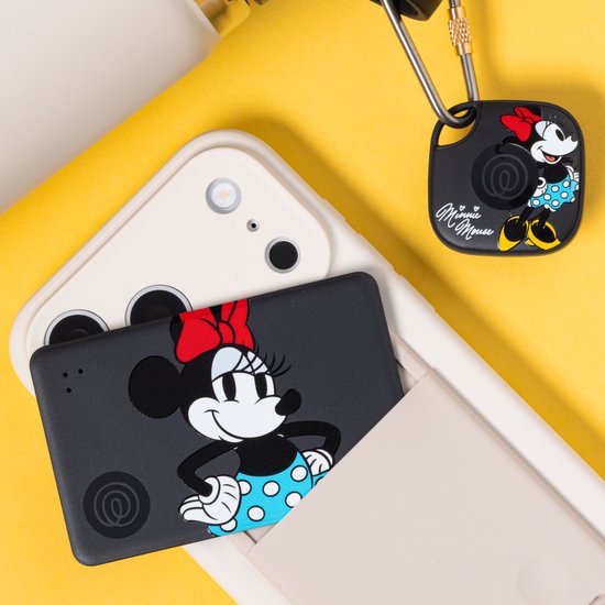 Een smartphone met een zwarte, platte Tile tracker en een zwarte Tile tracker met Minnie Mouse.