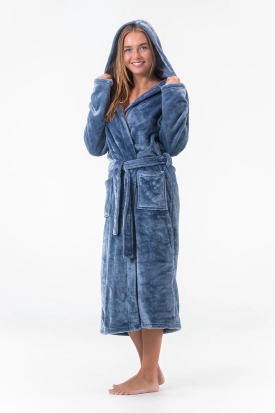 Une femme portant un peignoir bleu long à capuche, ceinture et poches, tirant sur la capuche.