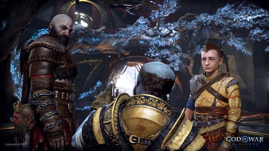 Kratos en Atreus kijken naar een man met gouden harnas in een besneeuwde, bosrijke omgeving.