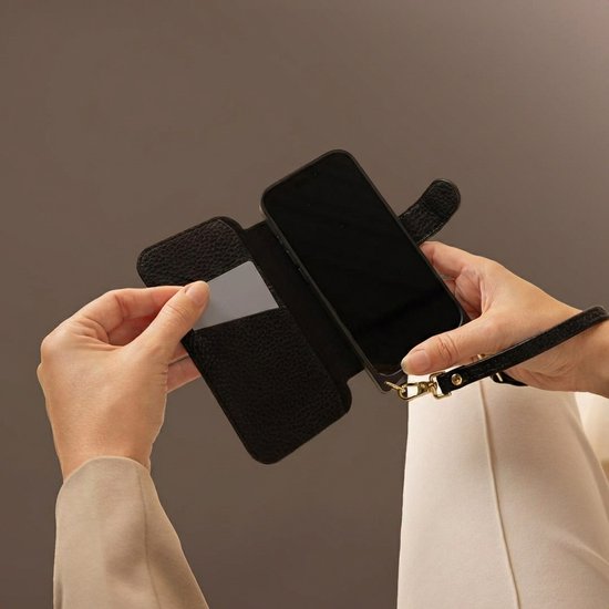 Handen plaatsen pasje in zwarte telefoonhoes met polsbandje.
