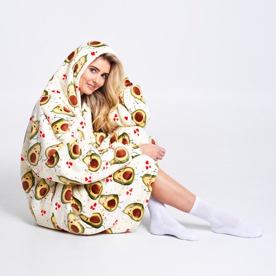 Vrouw in witte hoodie-deken met avocado-print, zittend op de grond.