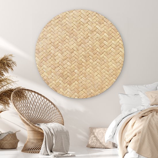 Décoration murale ronde imprimé rotin dans une chambre avec un fauteuil en rotin et un lit.