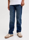 Detail van de onderbenen van een jongen in blauwe jeans.