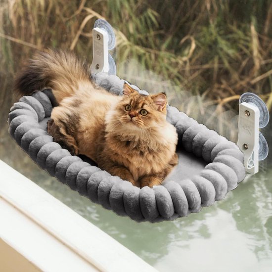 Langeharige kat in een grijze pluche hangmat met plooien aan het raam.