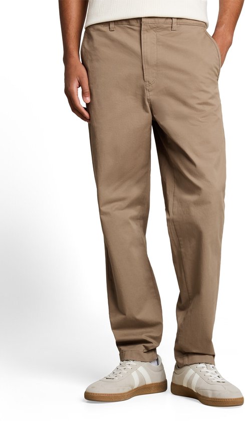 Voorpand van een beige chino, gedragen door een man.