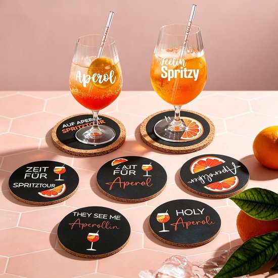 Six sous-verres ronds et noirs sur le thème des fruits et des boissons oranges. Deux verres d'Aperol Spritz reposent sur les sous-verres supérieurs.
