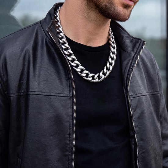 Man met leren jack en witte T-shirt, draagt een brede zilverkleurige schakelketting.