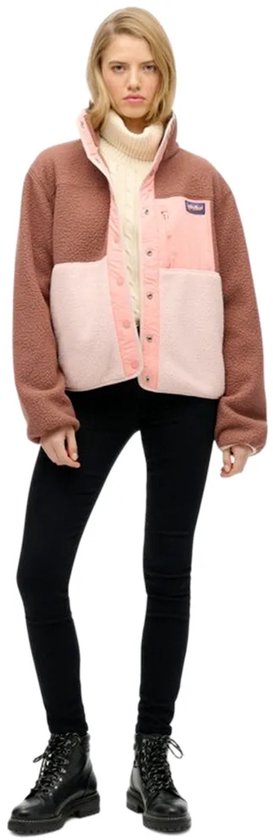 Model draagt bruine, roze en lichtroze fleece jas met spijkerbroek.