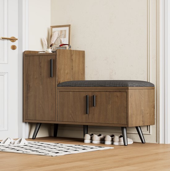 Meuble à chaussures en bois avec coussin d'assise gris foncé dans un couloir avec des chaussures en dessous.