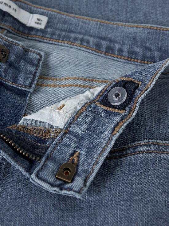 Sluiting en tailleband van een lichtblauwe jeans met knoop en ritssluiting.