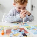 Jongen met gestreepte blouse gebruikt een oranje stempelstift op een Bluey kaart.