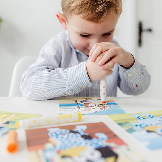 Jongen met gestreepte blouse gebruikt een oranje stempelstift op een Bluey kaart.