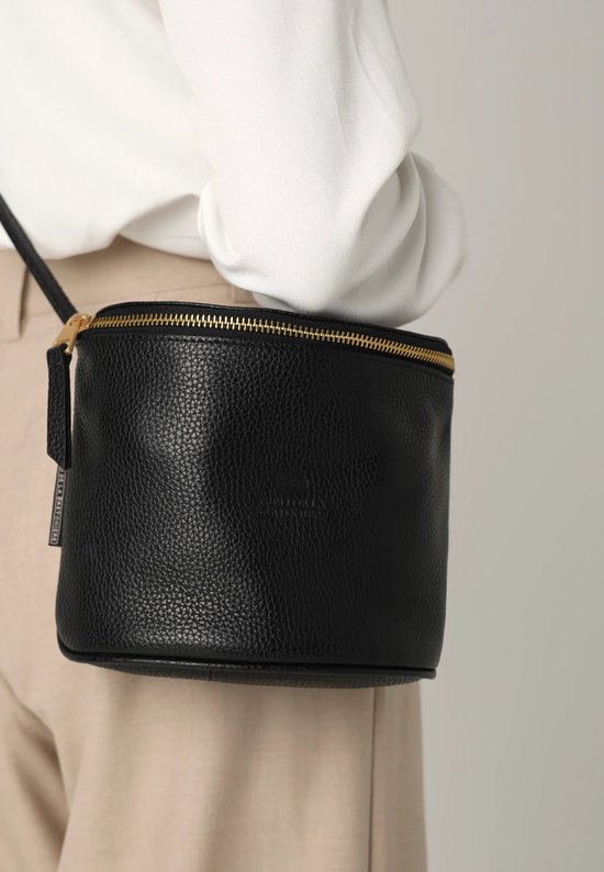 Model met zwarte Fred de la Bretoniere crossbodytas van leer met gouden rits.