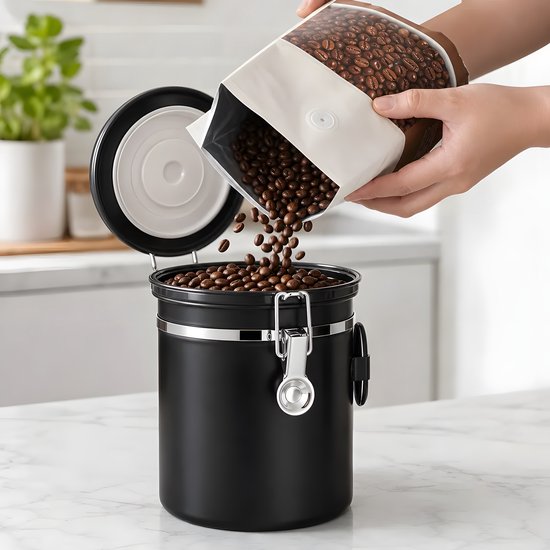 Een hand die koffiebonen uit een zak stort in de open zwarte RVS koffiebewaarpot.