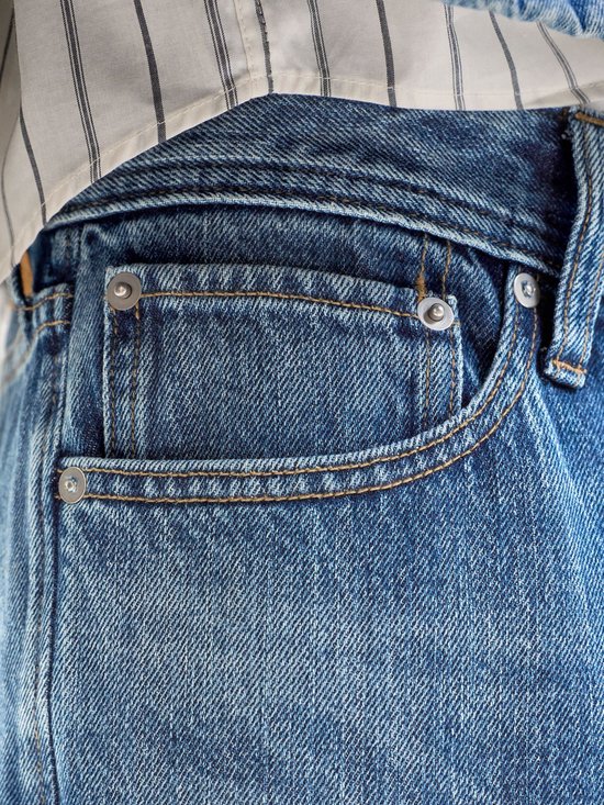 Detail van de zakken van een lichtblauwe spijkerbroek met klinknagels en stiksels.