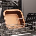Koperkleurige binnenpan en zwart grillrooster in een vaatwasser.