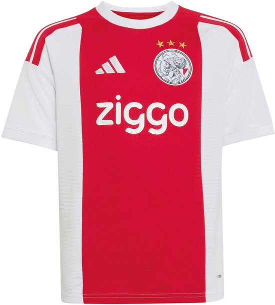 Ajax thuisshirt met rode baan op de voorkant, witte mouwen, clubwapen, drie Andreaskruizen en "ziggo" sponsor.