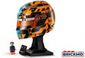 Blauw-oranje LEGO-helm met "OSCAR"-opschrift en oranje vizier, op een standaard met McLaren-logo.