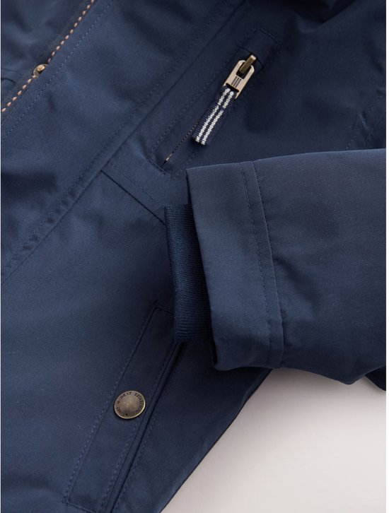 Detail van mouw en zak van donkerblauwe, waterdichte parka met gebreide boord.