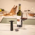 Zwarte Vacu Vin wijnstopper met een fles rode wijn en een glas.