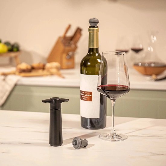 Zwarte Vacu Vin wijnstopper met een fles rode wijn en een glas.